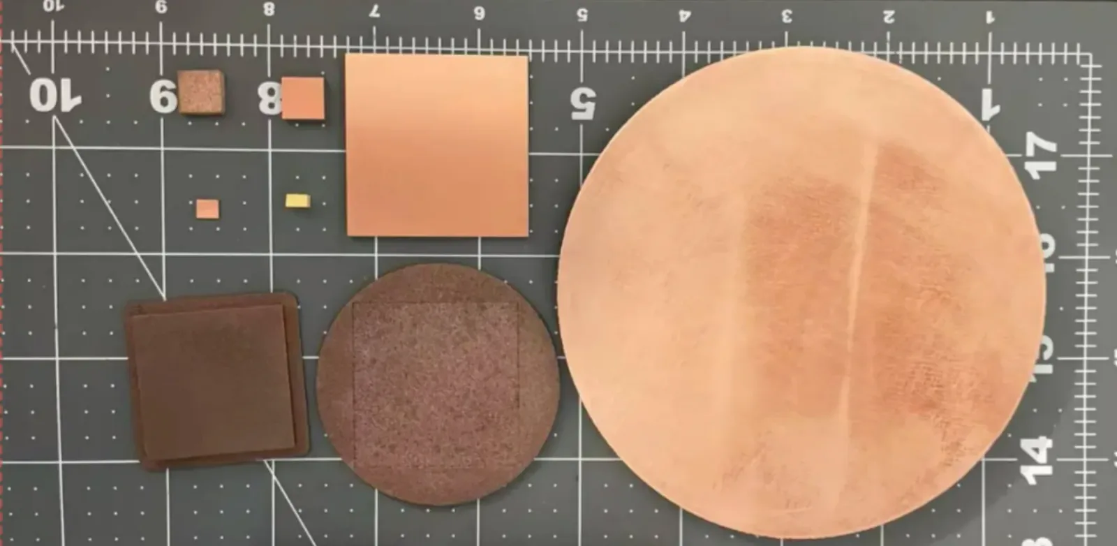 Project-supplied group of copper-tone circular, square and rectangular samples arranged on a measurement mat