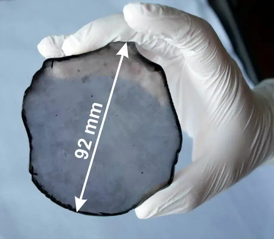 Independent reference photograph showing a circular CVD material specimen held for scale