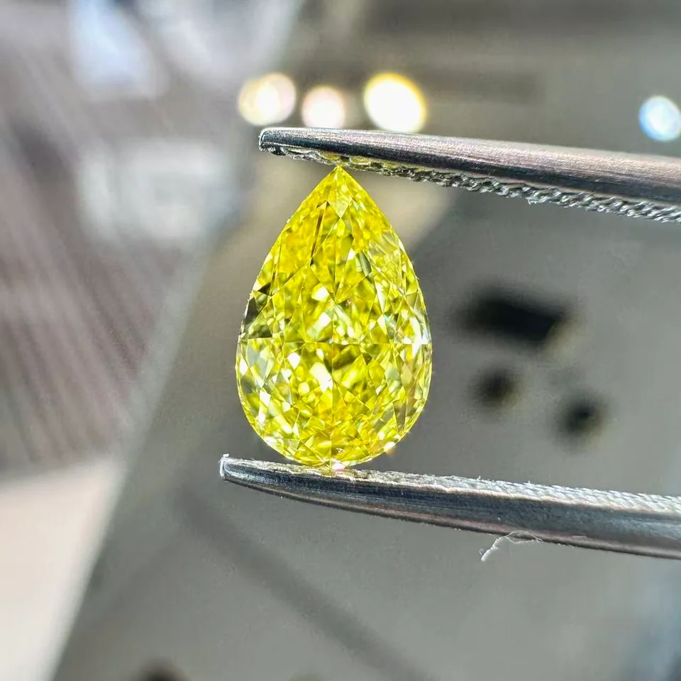 Yellow pear-shaped diamond held in tweezers